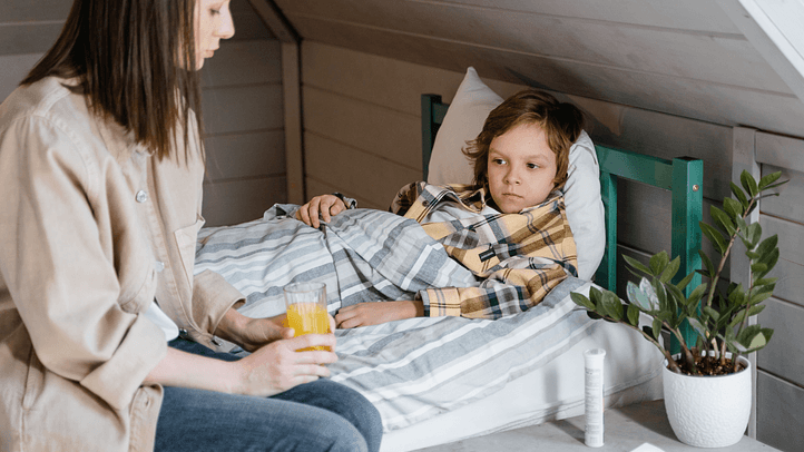 Mutter kümmert sich um ihr krankes Kind im Bett – Symbolbild für Kindergesundheit und den Umgang mit Erkrankungen im Kindesalter.